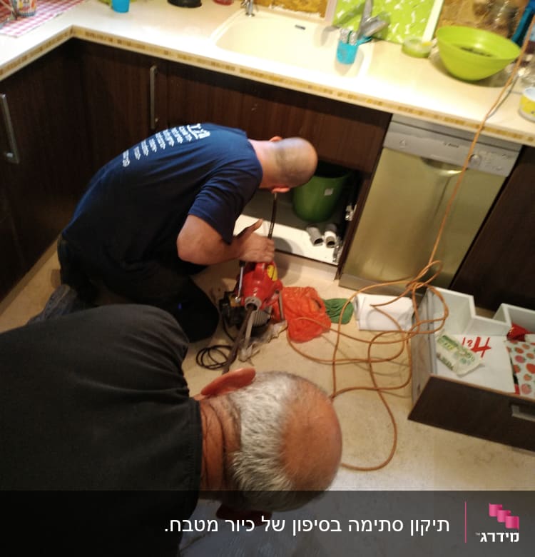 שני אינסטלטורים עובדים מתחת לכיור במטבח